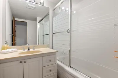 a white bathroom with a shower and a sink at 2BR Cozy Suite w Fireplace! FREE Banff Pass, Parking, Netflix! Near Golf Course! in Calgary