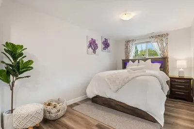 a white bedroom with a large bed and a plant at 2BR Cozy Suite w Fireplace! FREE Banff Pass, Parking, Netflix! Near Golf Course! in Calgary