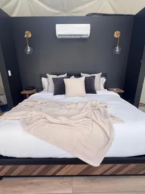 a bedroom with a large bed with a blanket on it at Experience Luxury Glamping at Ravines Edge Geo Glamping in Devon