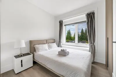 a white bedroom with a bed with a teddy bear on it at Charming and Modern Retreat in Vancouver Trendy 42nd Avenue Neighbourhood in Vancouver