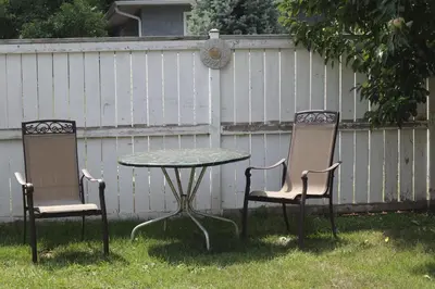 two chairs and a table in a yard with a fence at Calgary's Home Cinema Retreat in Calgary