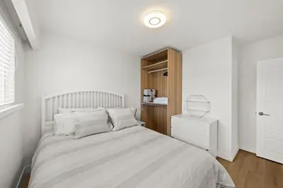 a white bedroom with a bed and a wooden cabinet at Cozy 3BR Holiday Retreat 2 Free Parking AC King BD in Vancouver