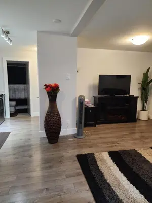 a living room with a vase with flowers in it at Cozy Royal Bay Suite in Victoria