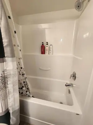 a bathroom with a white bath tub with a shower curtain at Cozy Royal Bay Suite in Victoria