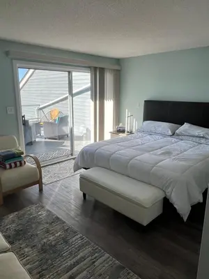 a bedroom with a large bed and a sliding glass door at Aloha Cottage, Nanoose Bay - 2 Bdrm Oceanfront Unit with Private Deck in Nanoose Bay