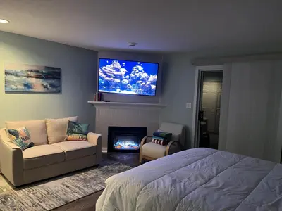 a bedroom with a bed and a tv above a fireplace at Aloha Cottage, Nanoose Bay - 2 Bdrm Oceanfront Unit with Private Deck in Nanoose Bay