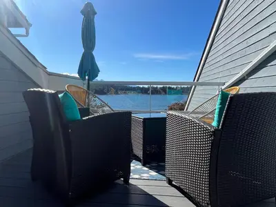a porch with two chairs and an umbrella at Aloha Cottage, Nanoose Bay - 2 Bdrm Oceanfront Unit with Private Deck in Nanoose Bay