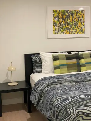 a bedroom with a bed and a table with a lamp at Almost Home in West Vancouver