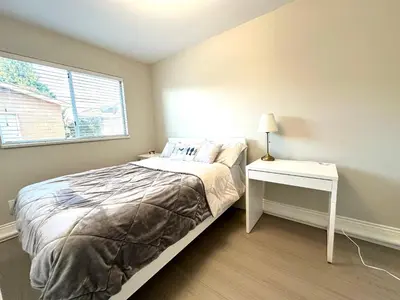 a bedroom with a bed and a nightstand and a window at Newly renovated 2 bed 1 bath in Ladner BC in Delta