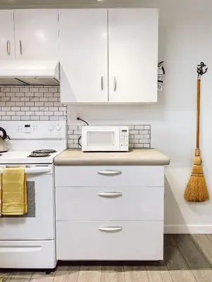 a white kitchen with white cabinets and a microwave at Swallow's Perch Guest Suite in Vesuvius