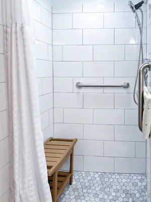 a bathroom with a shower curtain and a bench at Swallow's Perch Guest Suite in Vesuvius