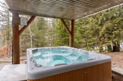 a hot tub sitting under a pergola at Cedar Ridge Estates by StayIn in Fernie