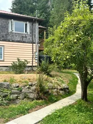 a house with a tree in front of a house at Silva Bay View BnB in Gabriola
