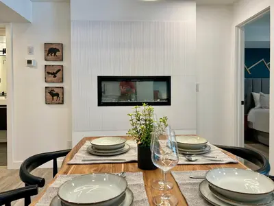 a dining room with a table with plates and glasses at Special! New Downtown Mtn View Free Parking 2b&2b in Canmore