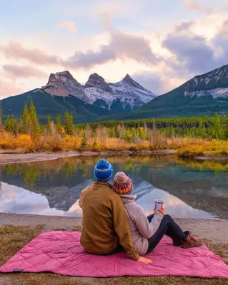 two people sitting on a blanket looking at the mountains at Special! New Downtown Mtn View Free Parking 2b&2b in Canmore