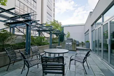 a patio with a table and chairs and a grill at Gorgeous City Views Central Studio Walk to Seawall in Vancouver