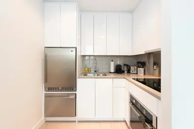a kitchen with white cabinets and a stainless steel refrigerator at Gorgeous City Views Central Studio Walk to Seawall in Vancouver