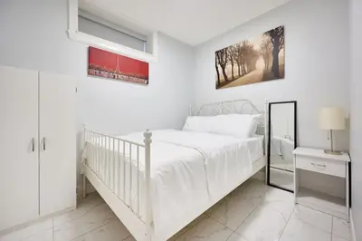 a white bedroom with a white bed and a mirror at Basement Suite In Vancouver in Vancouver