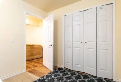 a bedroom with white closet doors and a rug at Basement Apartment in Calgary