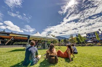 a group of people sitting on the grass in a field at Whistler Village 2BR 2BA Top-Floor Condo with Hot Tub and Parking in Whistler