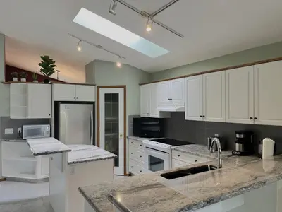 a kitchen with white cabinets and granite counter tops at Luxury bungalow in NW Calgary in Calgary
