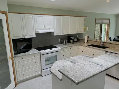 a kitchen with white cabinets and a counter top at Luxury bungalow in NW Calgary in Calgary