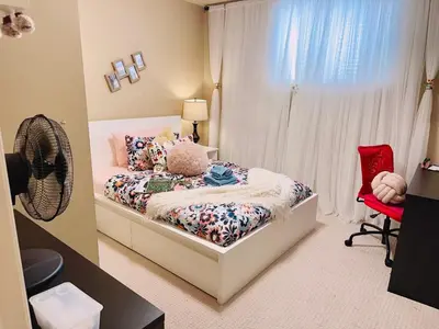 a bedroom with a bed and a red chair at Scorpio House Langley - Semi-basement Suite in Langley