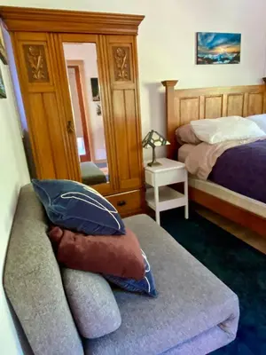 a bedroom with two beds and a couch and a mirror at Little Cabin in Middlepoint in Halfmoon Bay
