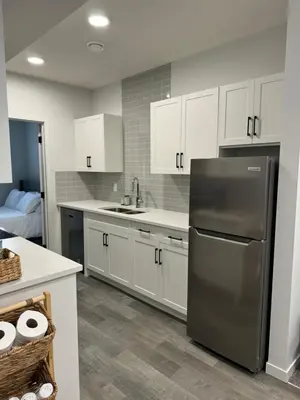 a kitchen with white cabinets and a stainless steel refrigerator at Chic & Cozy 2-BR Suite at Glacier Ridge NW Calgary in Calgary