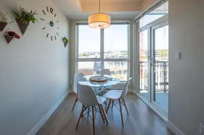 a dining room with a table and chairs and large windows at Stylish Modern Apartment In The Heart Of Old Town Victoria in Victoria