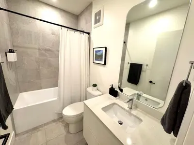 a white bathroom with a sink and a toilet at Central Moodyville Retreat in North Vancouver