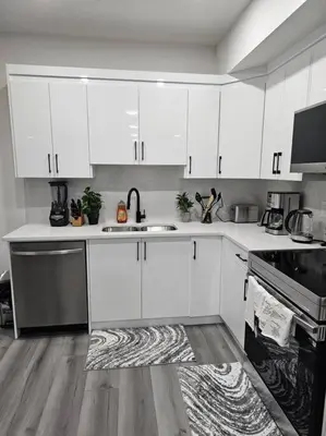 a kitchen with white cabinets and a black stove at Comfort Guest Suite NE Calgary - Near Airport in Calgary