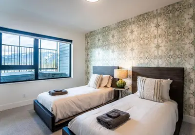 two beds in a bedroom with a window at Mountain Revelation by Revelstoke Vacations in Revelstoke
