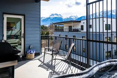 a view of mountains from a house balcony with a slide at Mountain Revelation by Revelstoke Vacations in Revelstoke