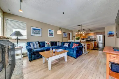 a living room with a blue couch and a table at Greystone Lodge 202 Ski-in Out in Whistler