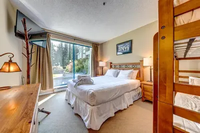 a bedroom with a bed and a large window at Greystone Lodge 202 Ski-in Out in Whistler