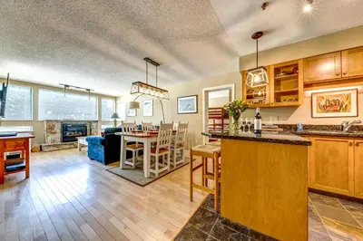 an open kitchen and living room with a dining room and a living room at Greystone Lodge 202 Ski-in Out in Whistler