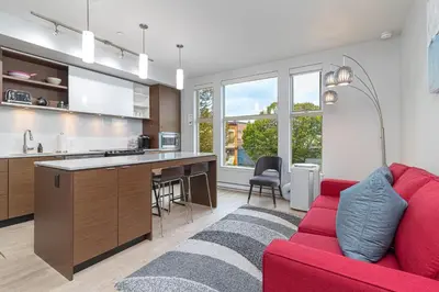 a living room with a red couch and a kitchen at Chic And Cozy Condo In Old Town Victoria in Victoria