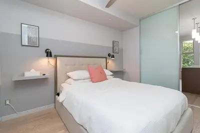 a bedroom with a large white bed with pink pillows at Chic And Cozy Condo In Old Town Victoria in Victoria