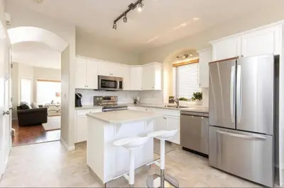a kitchen with white cabinets and a stainless steel refrigerator at Spacious 3bedrm for family or business travellers in Red Deer