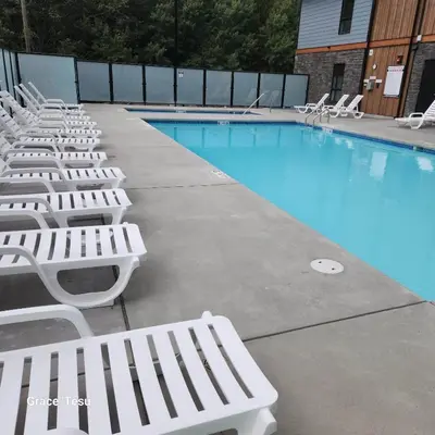 a row of white lounge chairs next to a swimming pool at Cozy Cove Retreat Escape to Tranquility Stay in Simplicity in Dead Man's Flats