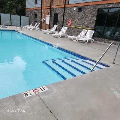 a swimming pool with lounge chairs next to a building at Cozy Cove Retreat Escape to Tranquility Stay in Simplicity in Dead Man's Flats