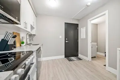 a kitchen with white walls and a black door at Modern Studio Unit - Close to DT in Edmonton