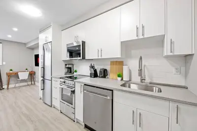 a kitchen with white cabinets and stainless steel appliances at Modern Studio Unit - Close to DT in Edmonton