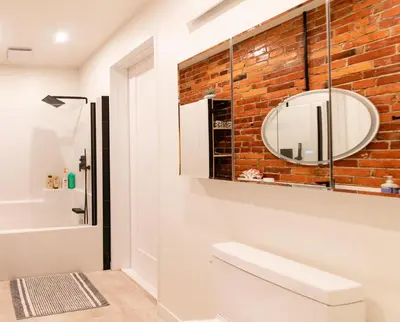 a bathroom with a brick wall and a mirror at Stylish downtown apartment in Grand Forks, BC in Grand Forks