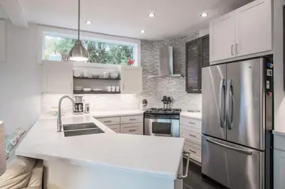 a kitchen with white cabinets and a stainless steel refrigerator at Christina Lake Lakefront, Hot Tub, Amazing Views in Christina Lake