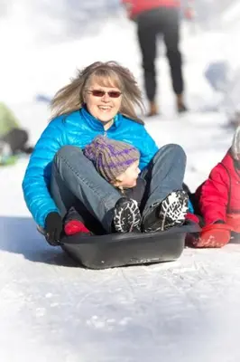a woman and a child riding on a snowboard at Christina Lake Lakefront, Hot Tub, Amazing Views in Christina Lake