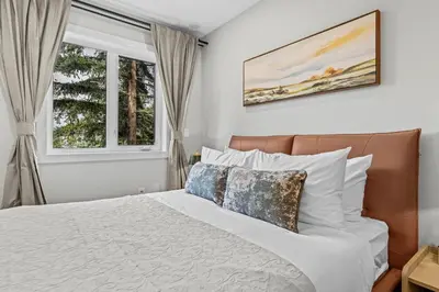 a bedroom with a bed and two windows at ML4- Private Rooftop Hot Tub Oasis- Entire townhouse with MTN View in Canmore