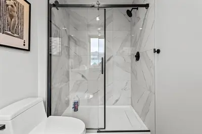 a white bathroom with a shower and a toilet at ML4- Private Rooftop Hot Tub Oasis- Entire townhouse with MTN View in Canmore