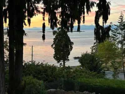 a view of the water from a house with trees at Tyee Beach Oasis Bed and Breakfast in Nanoose Bay